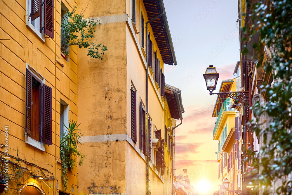 Rome, Italy. Ancient streets of old town. Vibrant houses with windows and street lamp at narrow Bright sunny summer evening during sunset.