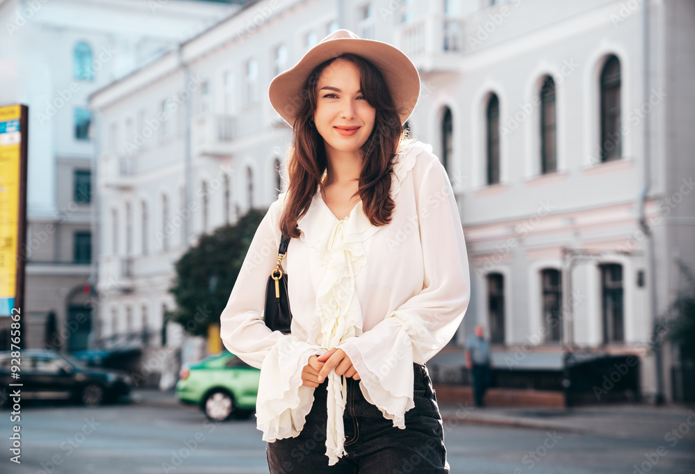 Obraz premium Portrait of young beautiful smiling hipster woman in trendy summer white blouse and jeans. Carefree woman posing in the street in sunny day. Positive model outdoors. Cheerful and happy, closeup