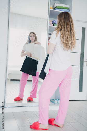 Vertical full length photo of teen blonde lady choose outfit mirror reflection dressed sleepwear apartment bedroom white light interior