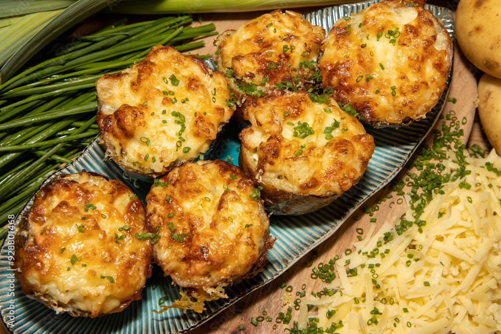 A selection of delicious Fish Pie Potato Skins topped with cheese and garnish on a wooden kitchen table background A selection of delicious Fish Pie Potato Skins topped with cheese and garnish on a wooden kitchen table background