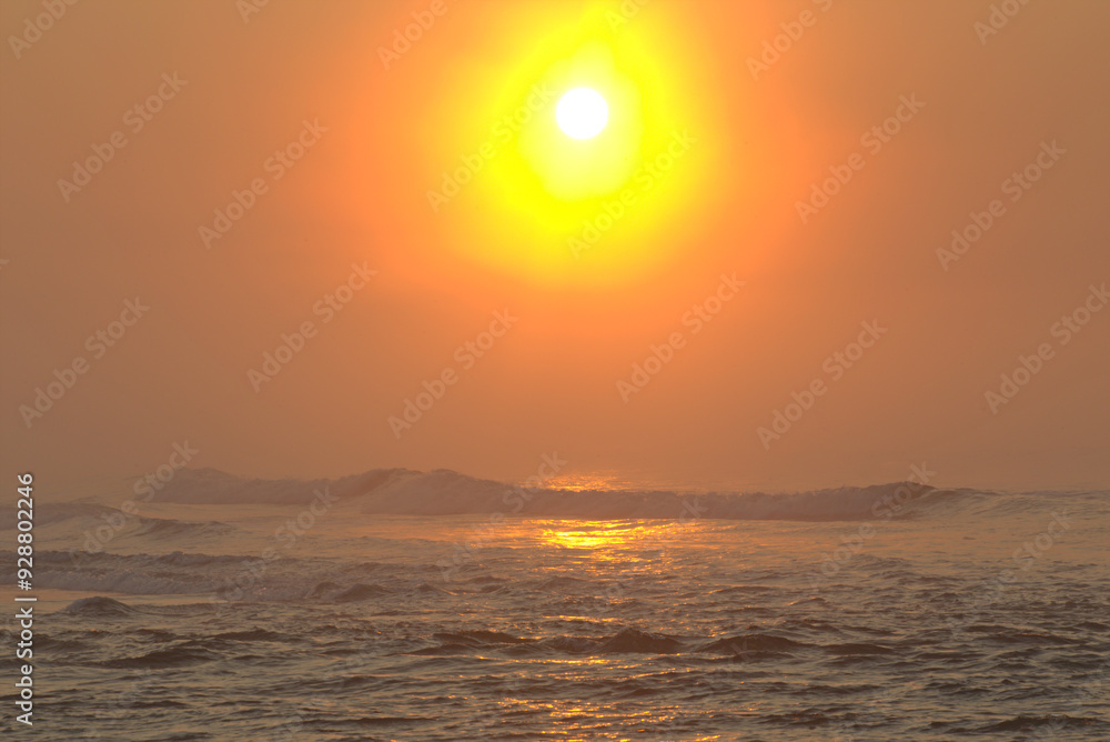 Bright reddish and orange light sunrise on the sea. Tropical beach of Itaguare, Bertioga, Brazil