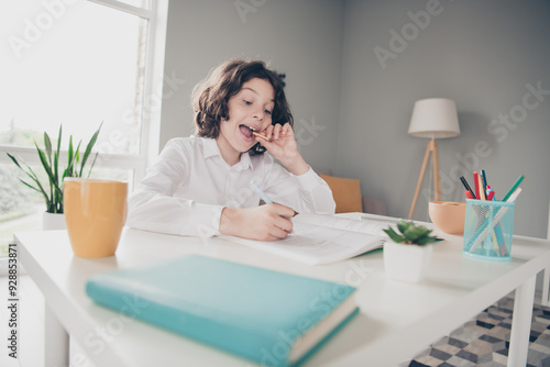 Photo of clever cute adorable small boy schoolkid doing hometask eating snack room interior indoors photo