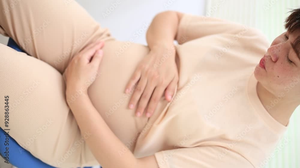 Detail of pregnant woman wearing white clothing and holding her belly with both hands.
Detail of pregnant woman wearing white clothing and holding her belly with both hands.