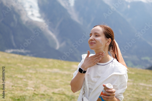 Young Hiker Is Applying Sunscreen On Her Face To Protect Her Skin From The Sun While Enjoying The Mountain View
