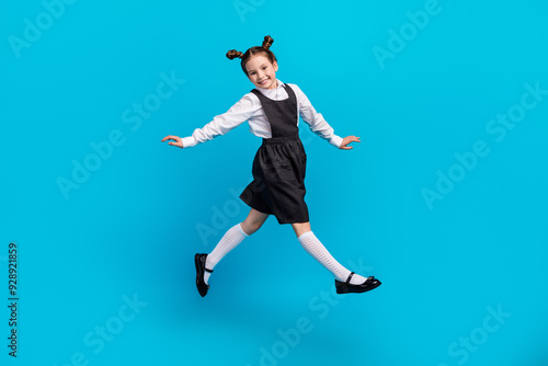 Full body photo of cute little girl jumping running carefree dressed stylish school uniform isolated on blue color background