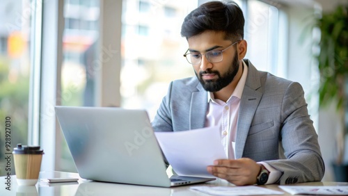 An Indian financial services specialist working with a laptop and financial papers. 