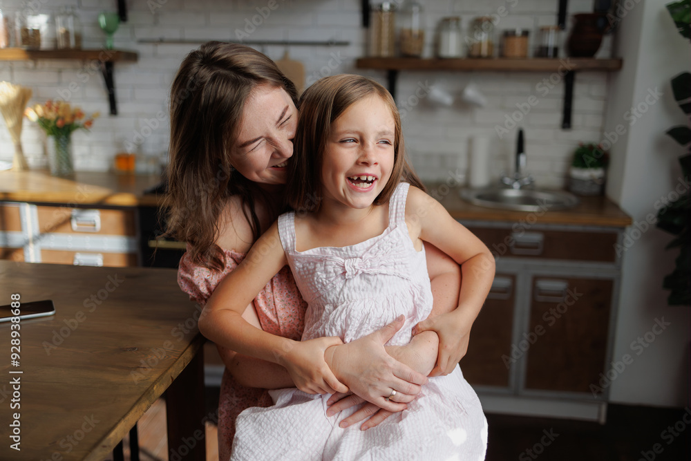 Positive mother hugging girl in kitchen at home