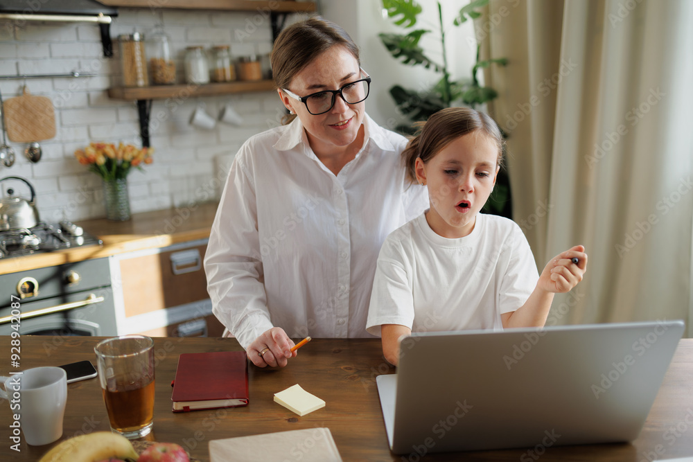 Girl using laptop during online education near mom at home Girl using laptop during online education near mom at home
