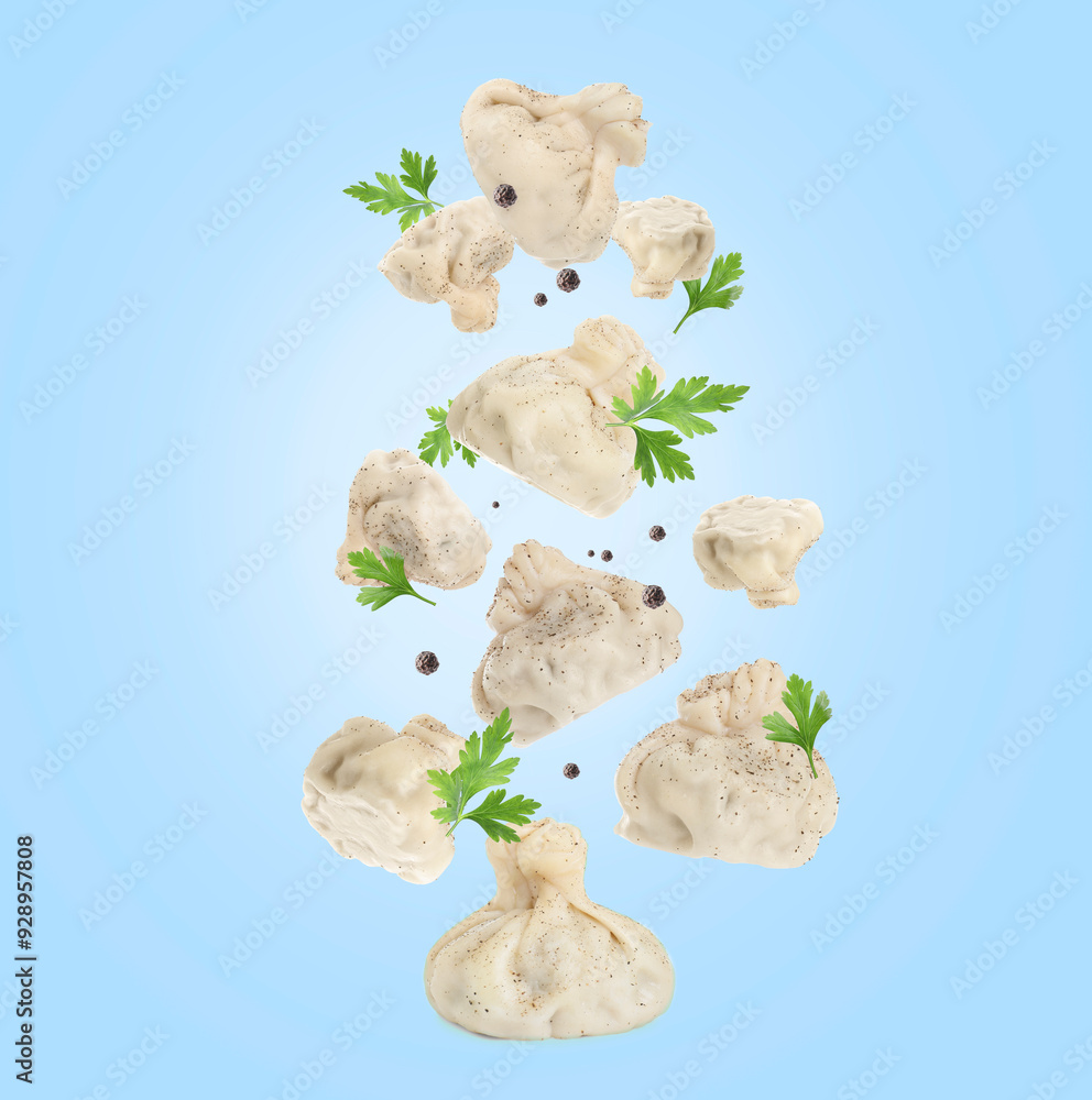 Fototapeta premium Delicious khinkali (Georgian dumplings), peppercorns and parsley falling on light blue background
