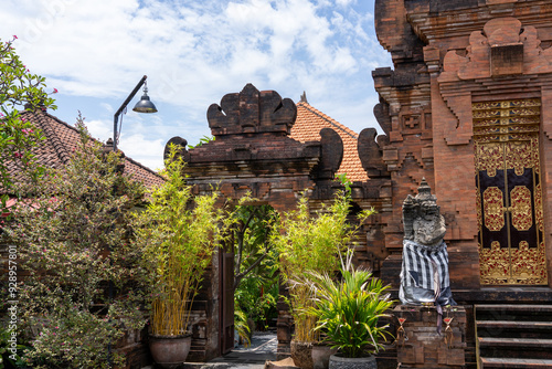 Angkul-angkul - Balinese home entrance gate. Door to house and temple Sanggah on Hindu Island of Bali, Indonesia. Brick Entrance, Ornate Gold Door, Statue with Sarong. photo