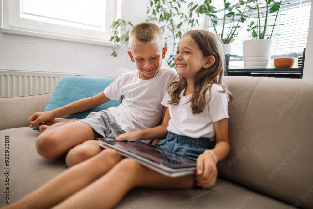 Obraz premium Two children sit on a sofa using tablet for entertaining