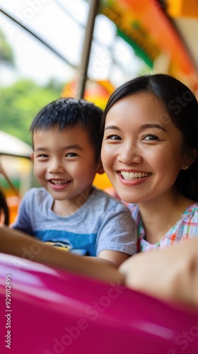 A joyful mother and her son share smiles while riding a colorful amusement park attraction