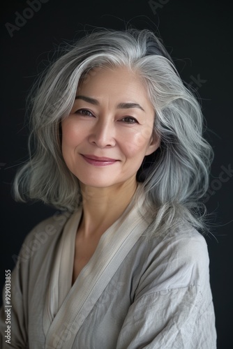 Asian woman with grey hair smiling against a studio background, highlighting Japanese adult female