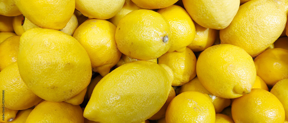The close-up photo showcases a vibrant, fresh lemon with its glossy, textured skin. The fruit's bright yellow color highlights its richness in vitamins, exuding freshness and zest against a soft backg The close-up photo showcases a vibrant, fresh lemon with its glossy, textured skin. The fruit's bright yellow color highlights its richness in vitamins, exuding freshness and zest against a soft backg