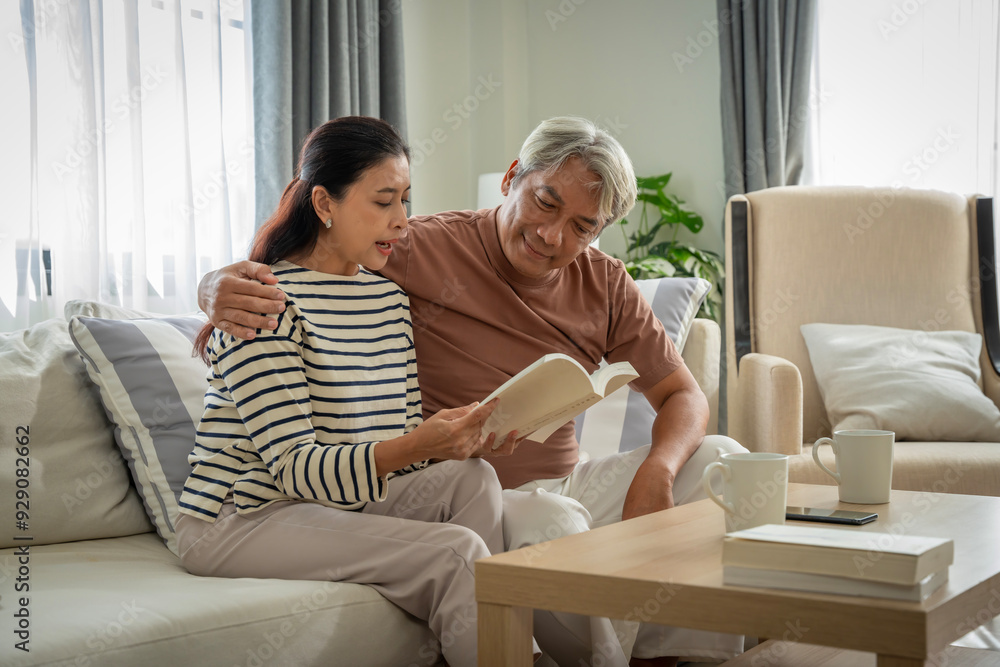 A man and woman are sitting on a couch reading a book together A man and woman are sitting on a couch reading a book together