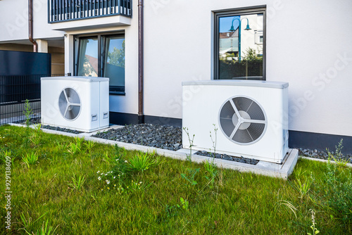 Two air source heat pumps installed outside of new and modern city house, green renewable energy concept of heat pump