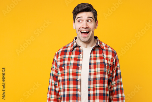 Young shocked surprised happy astonished jubilant cool Caucasian man he wear red checkered shirt casual clothes look aside on area mockup isolated on plain yellow orange background. Lifestyle concept