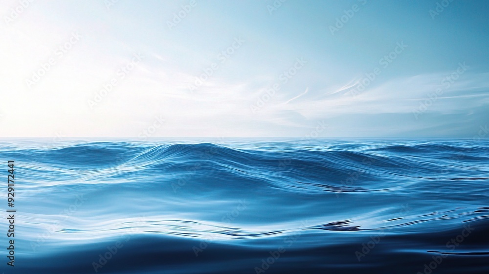 Fototapeta premium Tranquil Ocean Horizon: A vast and serene seascape, painted in soft hues of blue, stretches endlessly beneath a sky kissed by the golden glow of dawn. 