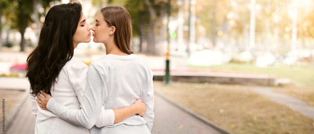 Fototapeta premium Lesbian Couple Of Girls Kissing And Hugging Having Romantic Date Walking In Park Outdoor. Back View