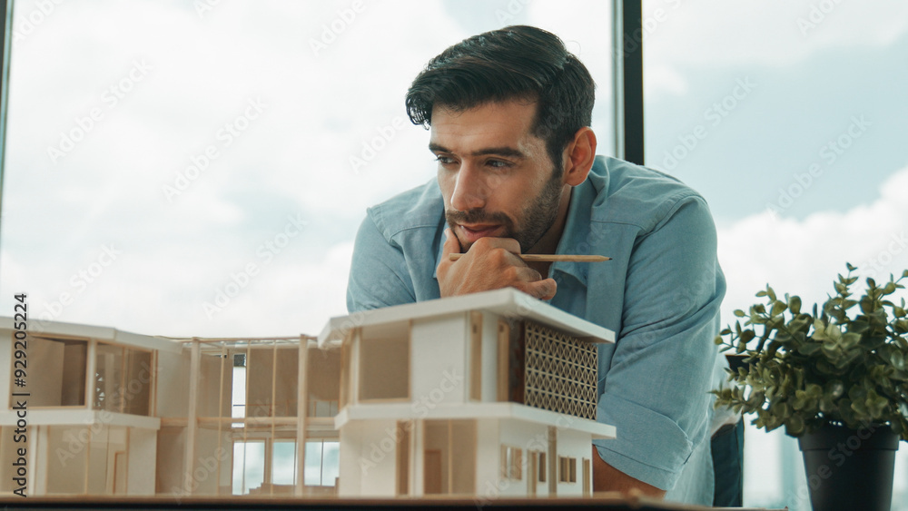 Smart caucasian engineer or project manager measure check, inspect, look at house model while standing near panorama window with city, skyscraper view. Manager design house construction. Tracery