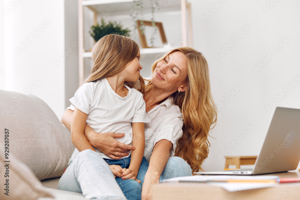 Mother and daughter bonding time on the couch while exploring educational content on a laptop together Mother and daughter bonding time on the couch while exploring educational content on a laptop together