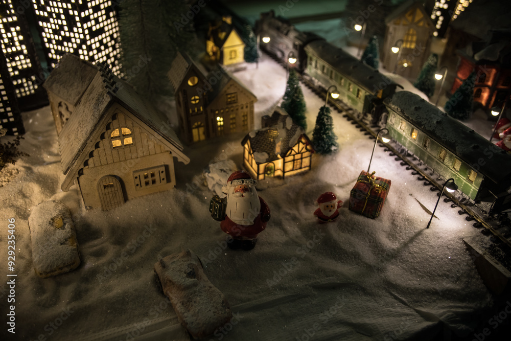 Naklejka premium Miniature of winter scene with Christmas houses, train station, trees, covered in snow. Nights scene. New year or Christmas concept.