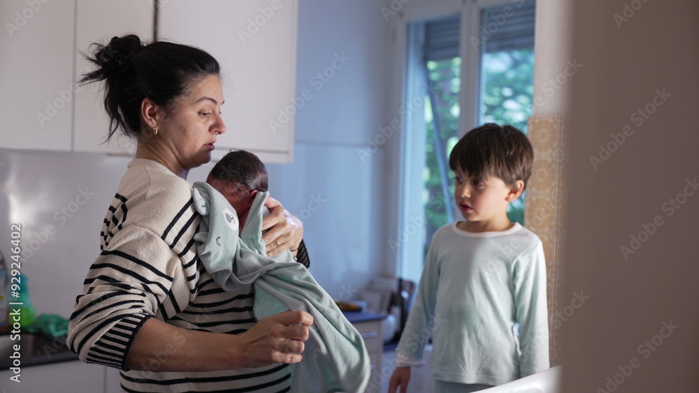 Mother carefully dressing her newborn baby after bath time, young sibling observing, capturing a tender family moment in the home Mother carefully dressing her newborn baby after bath time, young sibling observing, capturing a tender family moment in the home