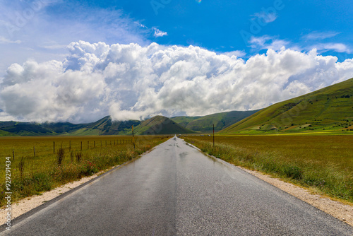 La lunga strada rettilinea che attraversa il Pian grande nell'altipiano di Castelluccio di Norcia, Umbria, Italia, a fine giugno 2024 photo