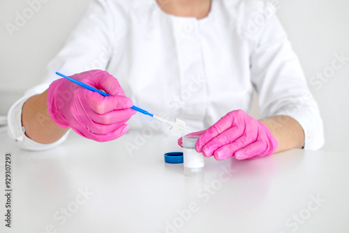 A gynecologist in pink gloves with a brush for taking a swab from the cervical canal for cytological abnormalities photo