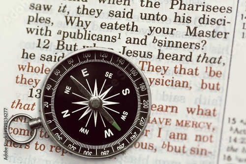 Canvas Print Hand holding retro compass and holy bible book.