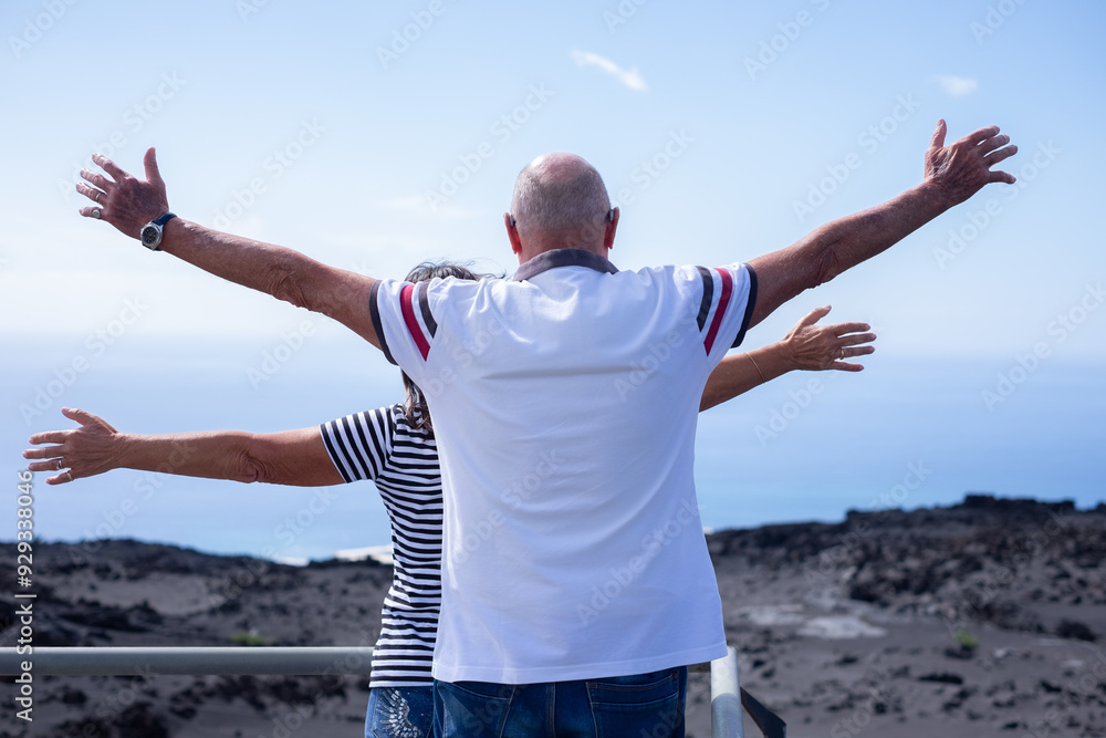 Rear view of Senior Caucasian couple with outstretched arms looking at horizon over sea. Elderly retirees enjoying Vacation Travel and Freedom. Retirement Lifestyle Concept Rear view of Senior Caucasian couple with outstretched arms looking at horizon over sea. Elderly retirees enjoying Vacation Travel and Freedom. Retirement Lifestyle Concept