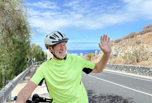 Happy attractive smiling active senior man riding an electric bicycle on the street. Elderly male enjoying healthy lifestyle and retirement or vacation. Horizon over sea