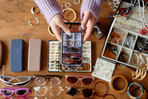 Girl taking photo of flat lay composition with vintage jewelry and fashion accessories, focus on phone screen, copy space photo