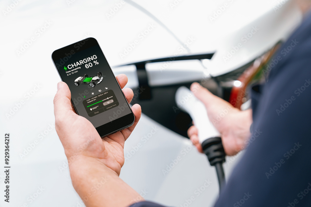 Man using smartphone online banking application to pay for electric car battery charging from EV charging station during vacation holiday road trip at national park or summer forest. Exalt Man using smartphone online banking application to pay for electric car battery charging from EV charging station during vacation holiday road trip at national park or summer forest. Exalt
