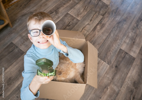 A small child, a boy, plays a pirate with a cat sitting in a box. Children's games in the children's room. Real friendship.