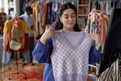 Quadro su tela Waist up shot of young smiling Middle Eastern woman trying vintage sweater vest