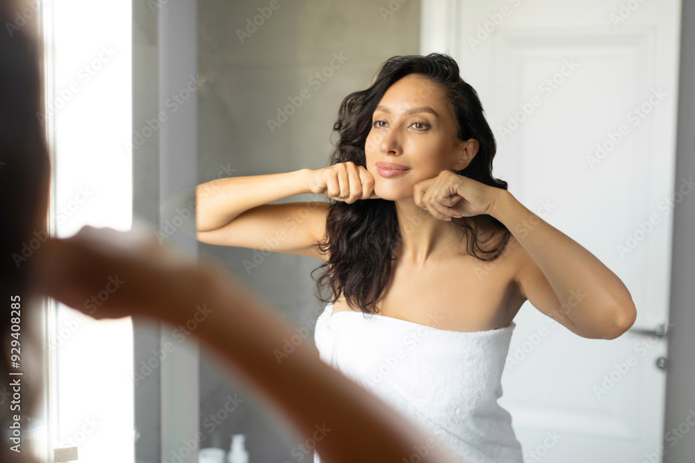 Woman making lymphatic drainage facial self massage in front of mirror in bathroom, lady doing domestic skin care treatment at bathroom Woman making lymphatic drainage facial self massage in front of mirror in bathroom, lady doing domestic skin care treatment at bathroom