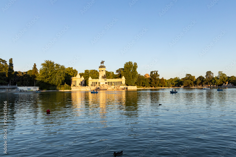 Obraz premium Retiro Park, Madrid, Spain. Crystal Palace, lake with swans, glass structure, architecture. Lake and temple on the horizon, fountains and decorated with colorful plants and flowers, family leisure.