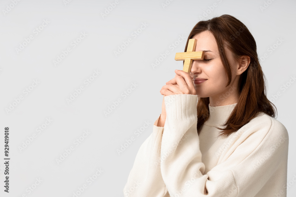 Religious young woman praying with wooden cross on white background Religious young woman praying with wooden cross on white background
