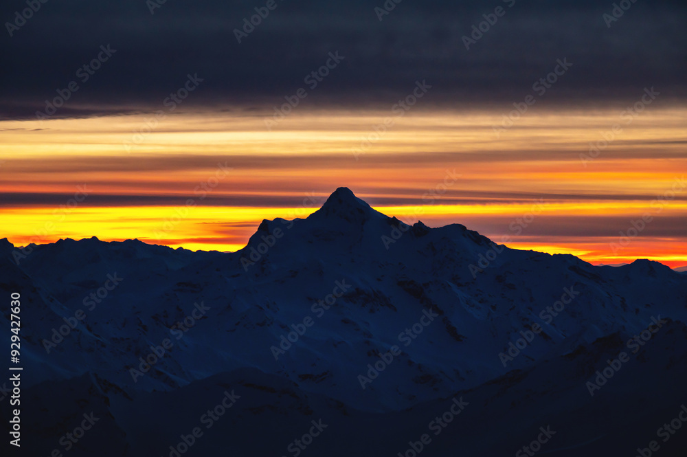 Sharp mountain peaks, silhouette of snow-capped mountains against the backdrop of a beautiful colorful sunset and clouds Sharp mountain peaks, silhouette of snow-capped mountains against the backdrop of a beautiful colorful sunset and clouds