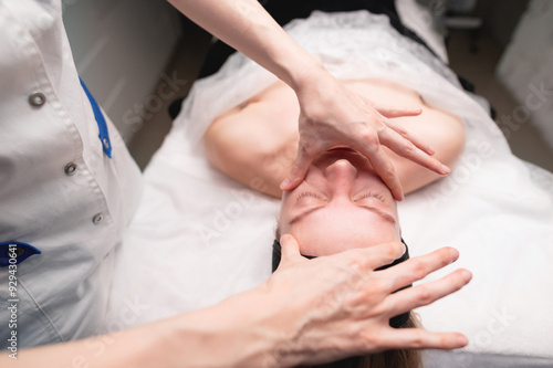 Facial massage beauty treatment. Close-up of a young woman face lying on back, getting face lifting massage, pinch and roll technique