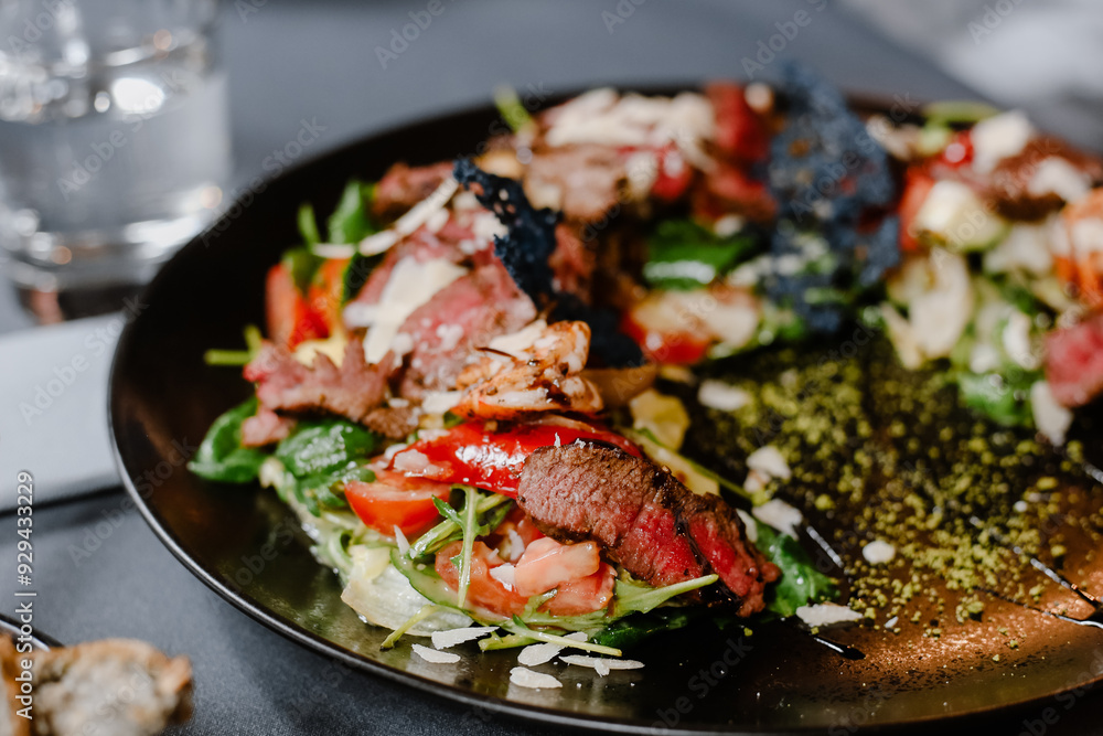 Beef salad with arugula and tomatoes on a black plate. Beef salad with arugula and tomatoes on a black plate.