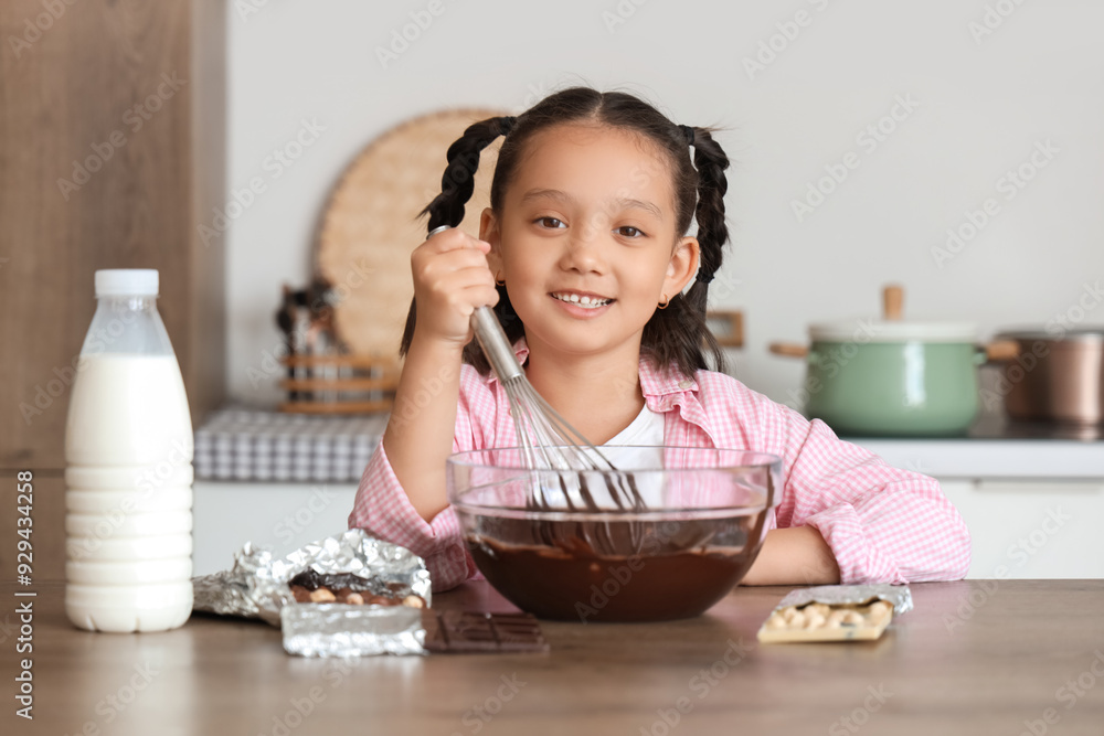 Cute little Asian girl whisking melted chocolate in kitchen Cute little Asian girl whisking melted chocolate in kitchen