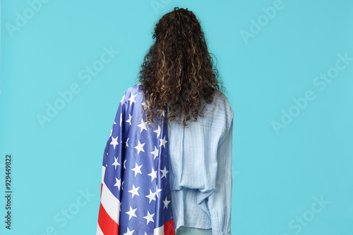 Beautiful young African-American woman with USA flag on blue background, back view photo