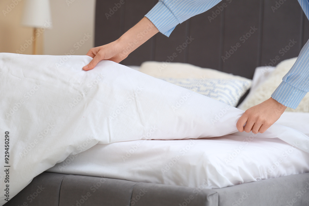 Young woman making bed in bedroom, closeup Young woman making bed in bedroom, closeup
