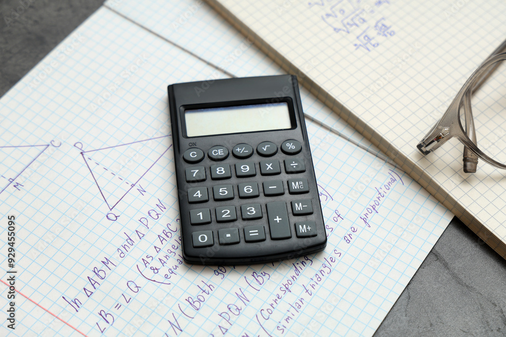 Copybooks with math formulas and calculator on table, closeup Copybooks with math formulas and calculator on table, closeup
