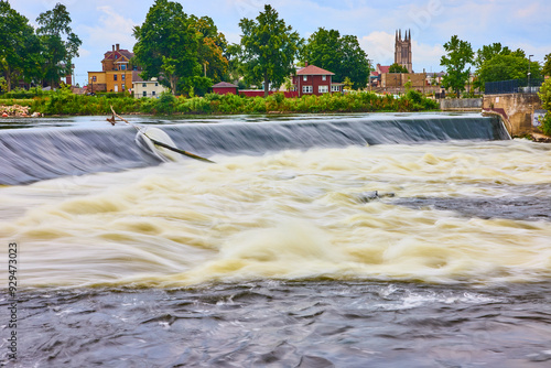 Flowing River Over Weir with Small Town Backdrop Eye-Level Perspective photo