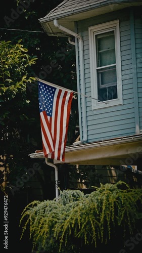 American Flag Hanging In Window Of Blue Home