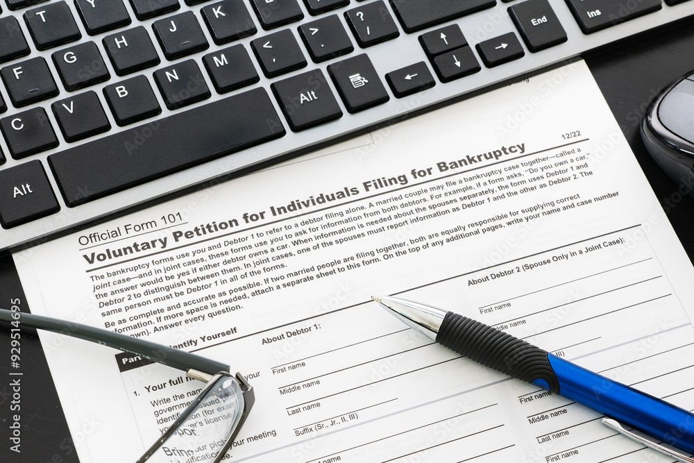 Close up of a bankruptcy form on desk with keyboard, mouse and pen Close up of a bankruptcy form on desk with keyboard, mouse and pen