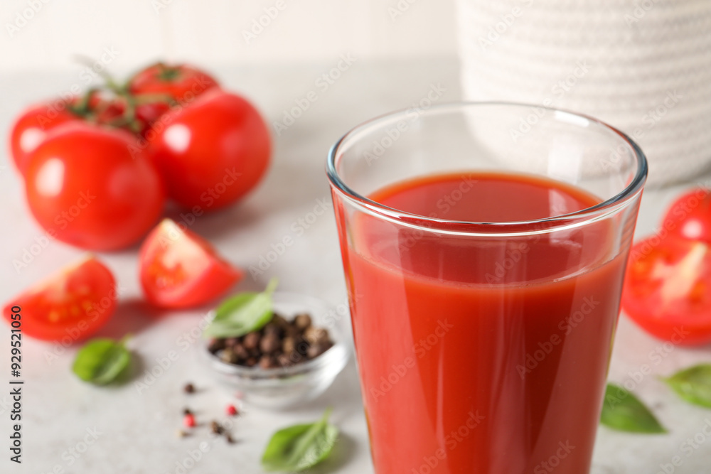 Tasty tomato juice in glass, basil leaves and fresh vegetables on table, closeup Tasty tomato juice in glass, basil leaves and fresh vegetables on table, closeup